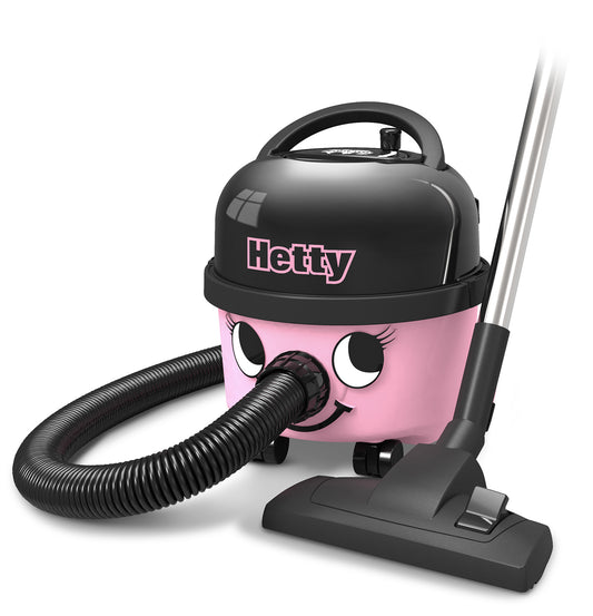 Der Hetty Compact Staubsauger HET160-11 der Numatic International GmbH ist ein rosa-schwarzer Kanistersauger mit einem lächelnden Gesicht, einem flexiblen Schlauch, einem fahrbaren Untersatz und einem Saugkopf, der neben dem Gerät auf dem Boden steht.