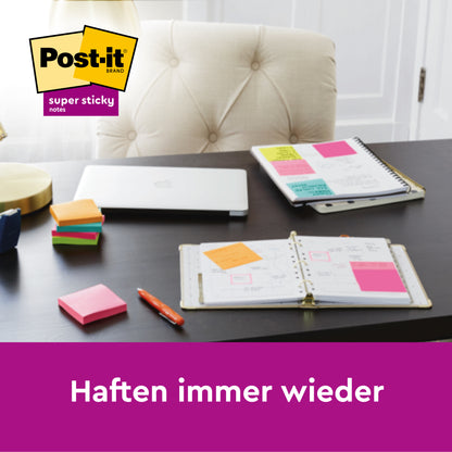 Ein Schreibtisch zeigt einen Planer und ein Spiralheft mit bunten Post-it® Super Sticky 100 % Recycling Notes (76x76 mm, 70 Blatt/Block, 3M Deutschland GmbH), einen geschlossenen Laptop, gestapelte Haftnotizblöcke, einen Stift und eine Lampe. Text: "Haften immer wieder.