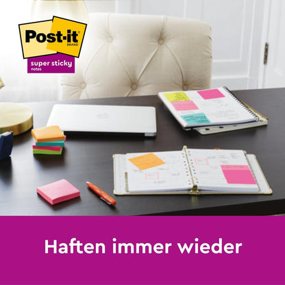 Ett skrivbord med 3M Deutschland GmbH Post-it® Super Sticky Notes (76 mm x 76 mm, 90 blad/block), anteckningsböcker, en stängd laptop och pennor. På de öppna anteckningsböckerna är flera lappar fastklistrade. Texten lyder: "Fäster om och om igen.