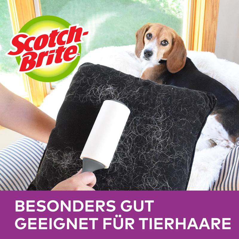 En person använder Scotch-Brite™ Pet Extra Sticky* Roller för djurhår (48 ark, 1 styck) från 3M Deutschland GmbH för att ta bort djurhår från en svart kudde. En hund ligger på soffan; logotyp och "SÄRSKILT LÄMPLIG FÖR DJURHÅR" visas ovanför.