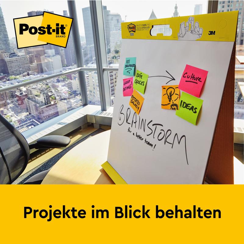 På kontoret med stadsutsikt står ett 3M Post-it® Super Sticky självhäftande mötesblock/flipchart med stativ (58,4x50,8 cm, 20 blad/block) - perfekt för anteckningar som "We Propose", "Save Spaces" och mer. Håll koll på projekt.