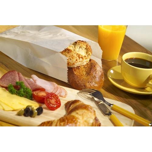Ein Frühstück mit Aufschnitt, Käse, Tomaten, Oliven, Croissant, Orangensaft und schwarzem Kaffee wird mit Brot in einem PAPSTAR 1000 Papierfaltenbeutel (Zellulose, gefädelt) der PAPSTAR GmbH auf einem Holztisch serviert.
