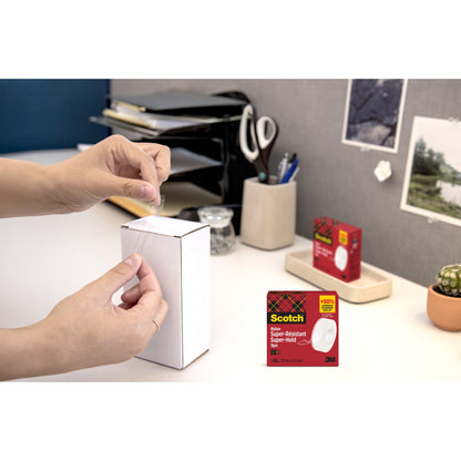 Eine Person verschließt eine weiße Schachtel mit Büromaterial mit Scotch® Super-Hold Secure Tape, 1 Rolle, 19 mm x 25,4 m von 3M Deutschland GmbH. Die Verpackung des Klebebandes ist in der rechten unteren Ecke eingefügt.