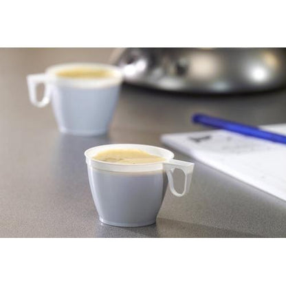 Två vita Starpak 60 kaffekoppar (0,18 l, PS, Ø 7,8 cm, 6 cm), en i fokus och en suddig i bakgrunden, står på en grå yta, på höger sida syns delvis en penna och papper.