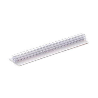 Orkla Wound Care AB Clip signera | Förpackning (1 styck) är en genomskinlig hyllmärkeshållare av plast med en platt bas och ett vertikalt spår för etiketter, perfekt för att organisera eller märka artiklar. Avbildad mot en vit bakgrund.