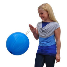 En leende flicka med långt blont hår och en blågrå skjorta leker med en stor PAPSTAR punchballong (Ø 40 cm, färgsorterad, 3-set) från PAPSTAR GmbH mot en vit bakgrund.