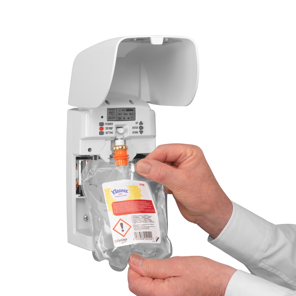 Eine Person steckt ein Kleenex® Duft Joy Nachfüllpack (300 ml, Transparent) der Kimberly-Clark GmbH in einen weißen Wandspender und sorgt mit sichtbaren Tasten und Kontrollleuchten für lang anhaltende Frische.
