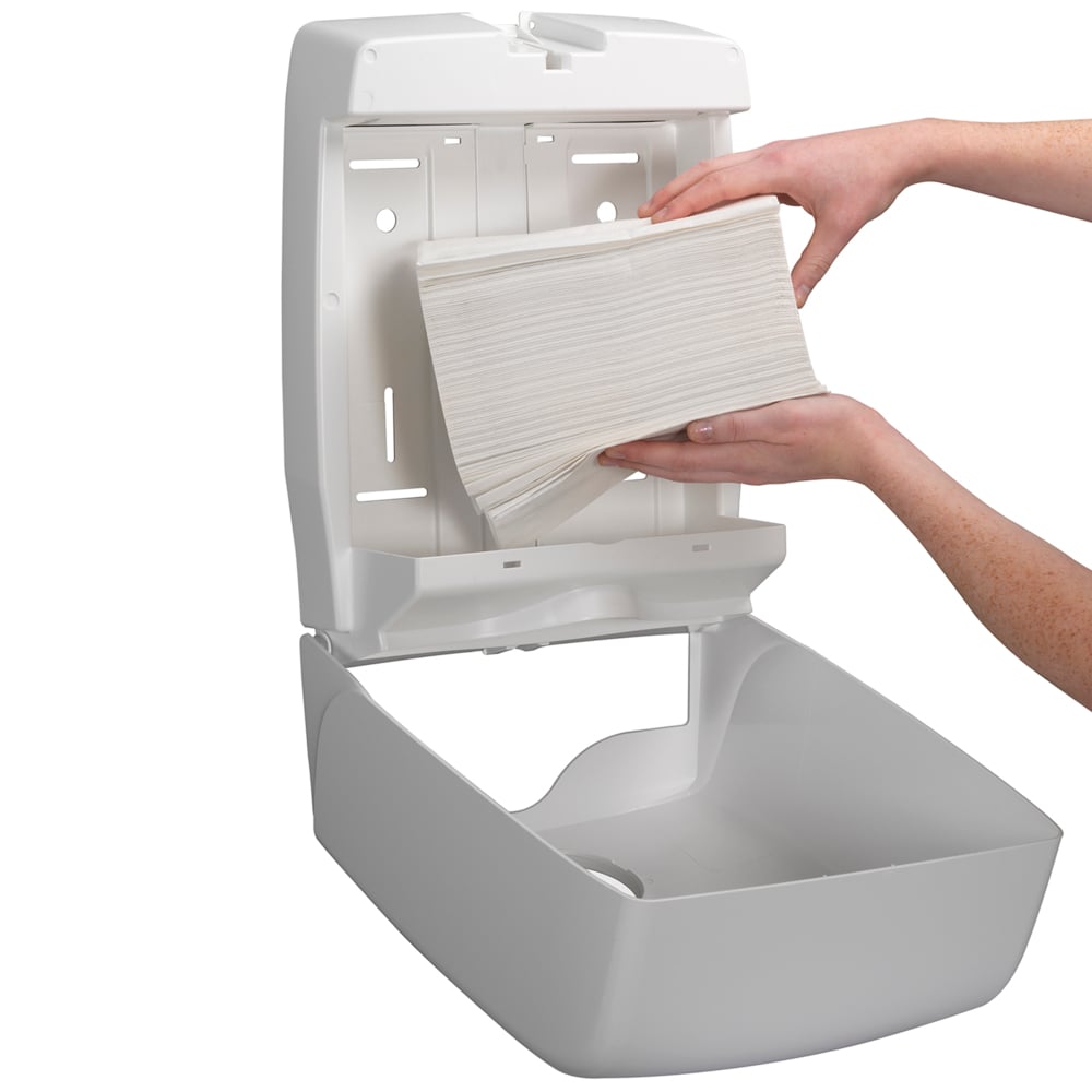 En person fyller på en väggmonterad dispenser med Kleenex® Ultra™ vikta handdukar Interfold vit (15 clips x 96 ark) från Kimberly-Clark GmbH och säkerställer hygienisk handtorkning, eftersom den öppna dispensern möjliggör enkel påfyllning.