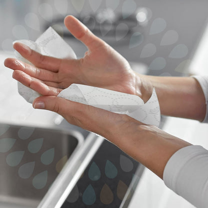 Någon torkar händerna över diskbänken med Kleenex® Ultra™ vikta handdukar Interfold (vit, 15 clips x 96 ark) från Kimberly-Clark GmbH, medan ett vattendroppsmönster betonar den hygieniska handtorkningen.