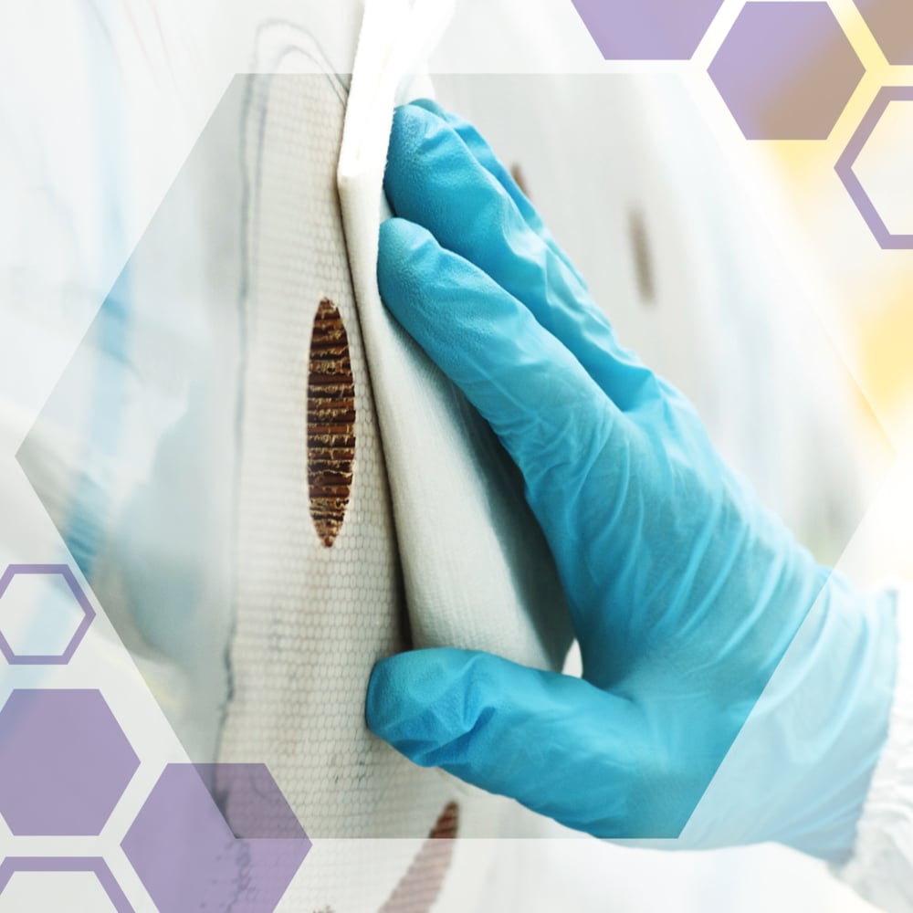 En hand med handskar rengör en cirkulär brun fläck på en vit yta med Kimtech® Science precisionsservetter från Kimberly-Clark GmbH. Halvtransparenta hexagoner är lagda över bilden.