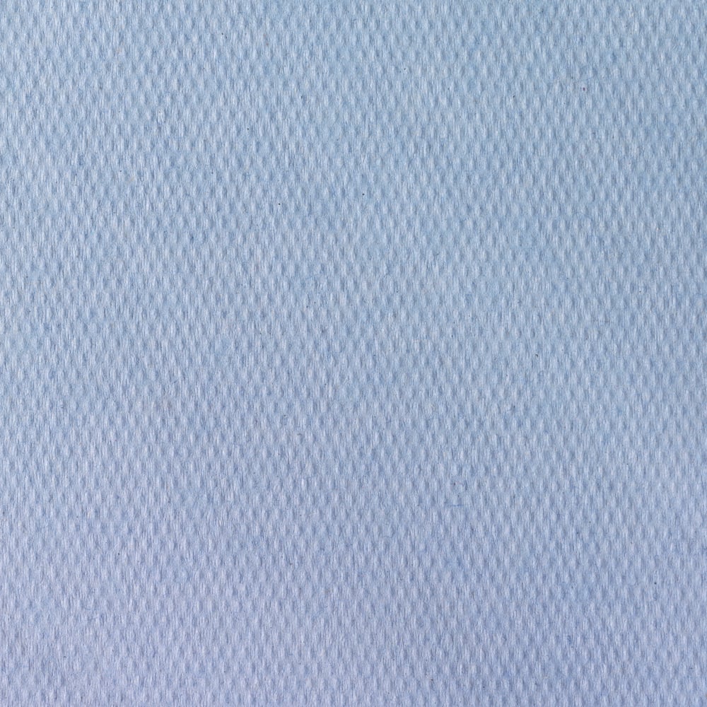 Närbild av Scott® läkarrullar från Kimberly-Clark GmbH (38,00 cm x 51,00 cm), ett ljusblått, strukturerat tyg med diskret diamantmönster, som ofta används för undersökningsbäddar i medicinska anläggningar. Den släta ytan fyller ramen.