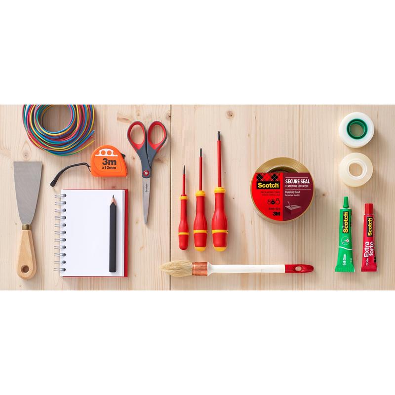 En platt läggning visar olika verktyg och hjälpmedel på trä, inklusive Scotch® förpackningstejp (50 mm x 66 m) från 3M Deutschland GmbH, sax, skruvmejsel, pensel, lim, spackel, färgad tråd, anteckningsbok med blyertspenna och andra band.