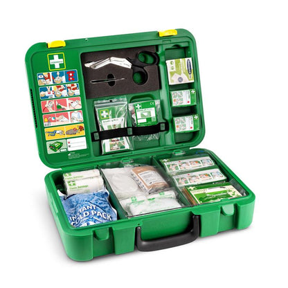 En öppen grön Orkla Wound Care AB Första hjälpen-låda DIN | Förpackning (1 styck) innehåller förband, gasväv, antiseptiska servetter, saxar, en omedelbar kylpåse, tejp, handskar och en första hjälpen-guide i locket.