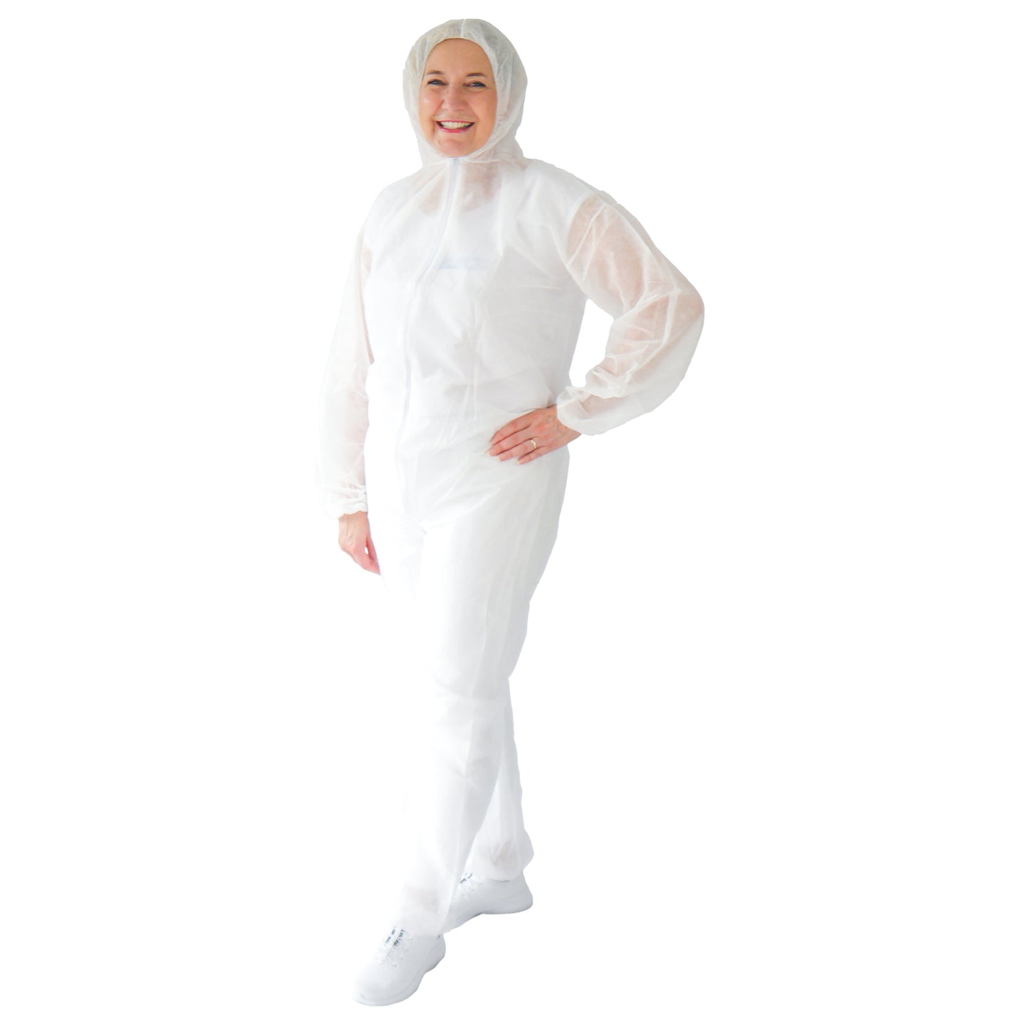 En person står leende i en ARNOMED COVER PP-OVERALL WHITE engångsoverall med huva av PP-fleece i vitt från ARNOWA GmbH, ihopparad med vita skor. Bakgrunden är enfärgad vit.