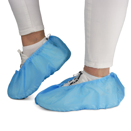 En person bär vita byxor och sneakers med ARNOMED ABS-skoskydd från ARNOWA GmbH. De halkfria engångsskydden (påsar om 100 stycken) skyddar både skor och golv – perfekta för hygieniska miljöer.