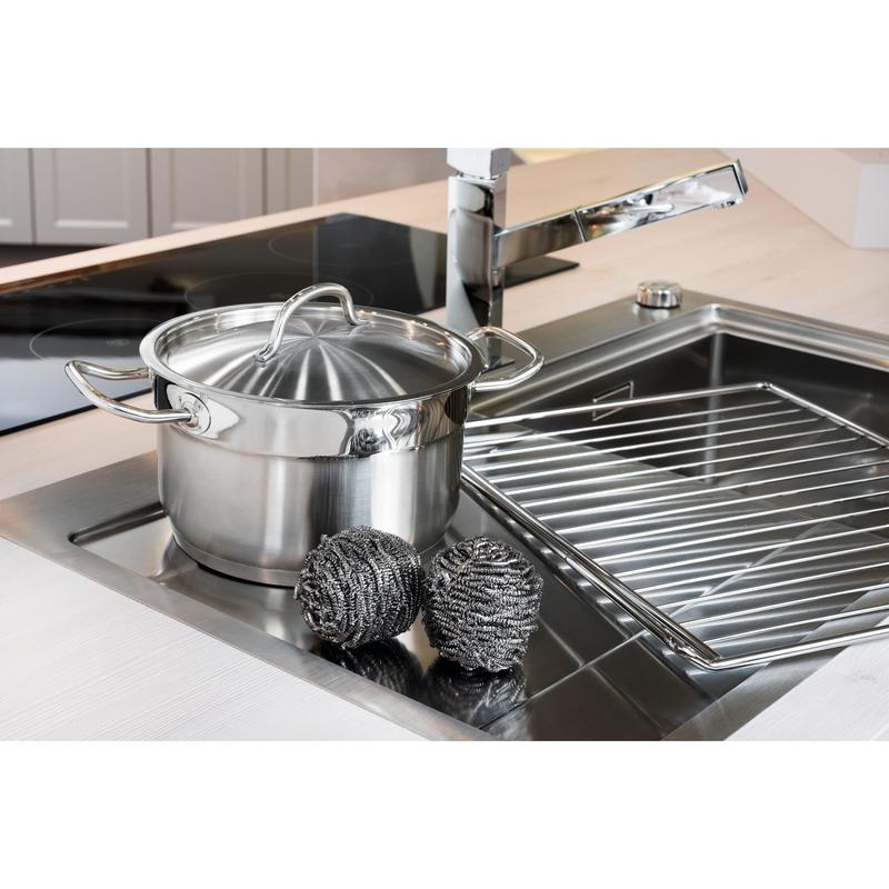 En rostfri gryta med lock står i diskhon bredvid två Scotch-Brite® rostfritt stålspiraler (3M Deutschland GmbH, 3 stycken per förpackning) och ett diskställ - för enkel köksrengöring även vid envis smuts.
