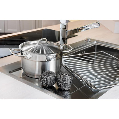 En rostfri gryta med lock står i diskhon bredvid två Scotch-Brite® rostfritt stålspiraler (3M Deutschland GmbH, 3 stycken per förpackning) och ett diskställ - för enkel köksrengöring även vid envis smuts.