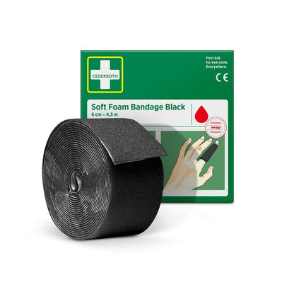 En rulle Cederroth mjukt skumbandage svart (6 cm x 4,5 m) från Orkla Wound Care AB är utställd framför den grön-vita lådan, där en hand med det svarta bandaget är lindad runt ett finger.