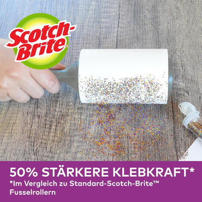 En hand använder Scotch-Brite™ Pet Extra Sticky* Roller för djurhår från 3M Deutschland GmbH (48 ark) för att ta bort spilld glitter från en träyta. Tysk reklam: 50 % starkare klibbighet än standardmodeller.