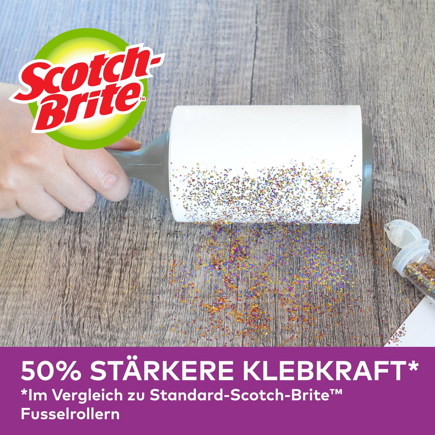 En hand använder Scotch-Brite™ Pet Extra Sticky* reservrulle för djurhår (48 blad, 1/förpackning) från 3M Deutschland GmbH för att ta bort spillt glitter från trä. En öppen glitterbehållare är i närheten. "50% starkare klisterkraft" jämfört med standardrullarna nedan.