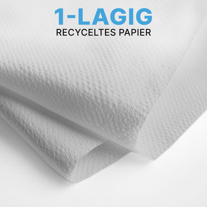 Närbild av två vita ARNOMED PAPPERHANDDUKAR (25 x 23 cm, V-FALZ) från ARNOWA GmbH med strukturerad yta, staplade i V-falz. Den blå-svarta texten lyder "1-LAGERS ÅTERVUNNET PAPPPER" - idealiskt för tvättrum.