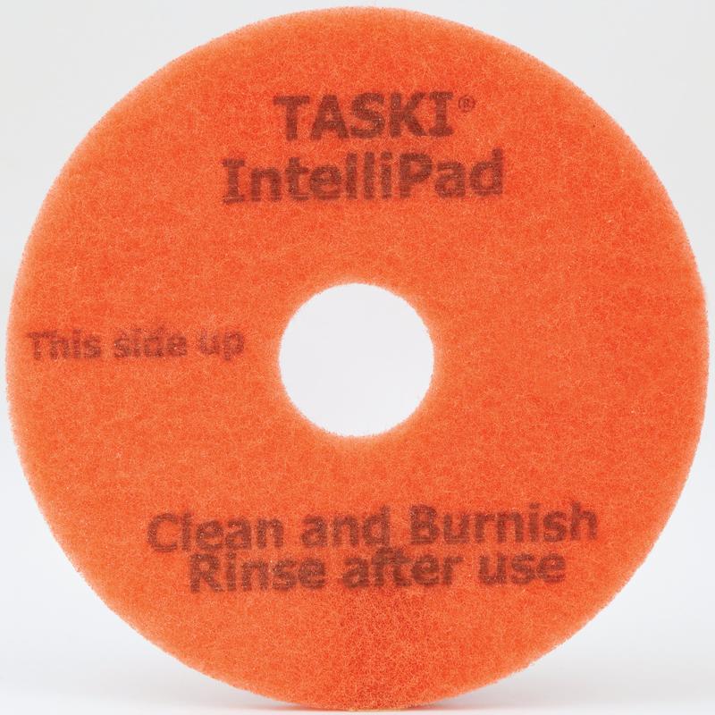 Den TASKI Intellipad Kombinerade rengörings- och polerpad för underhållsrengöring från Diversey Deutschland GmbH & Co. OHG är en orange, cirkulär pad med ett hål i mitten och texten "TASKI IntelliPad", "This side up" och "Clean and Burnish, Rinse after use" i grå skrift.
