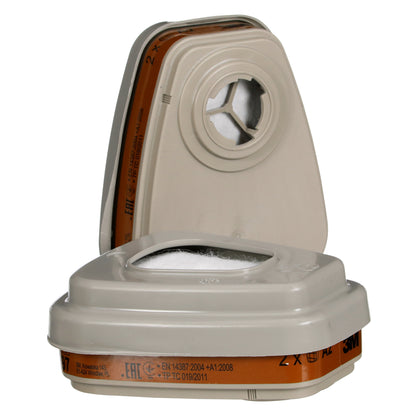 Abgebildet sind zwei beigefarbene 3M™ Filtersätze 6003-1 der 3M Deutschland GmbH mit orangefarbenen Bändern, einer stehend und einer liegend, beschriftet für A2P3 Schutz gegen organische Dämpfe; beide mit zentraler Öffnung und Sicherheitshinweis.