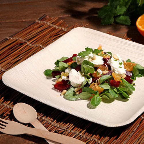 En stilfull PAPSTAR 25 tallrik, Palmblad "pure" från PAPSTAR GmbH, serverar en färsk sallad på en vävd bordstablett – idealisk för speciella tillfällen med sin miljövänliga design.