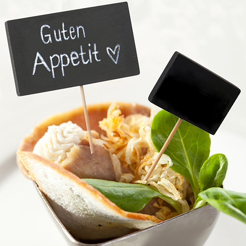 Ein kleines Schälchen mit Blattgemüse, knusprigen Röstzwiebeln, Brot und weißem Aufstrich enthält zwei PAPSTAR 100 Fingerfood - Picker Sticks der PAPSTAR GmbH - auf dem einen steht "Guten Appetit ♥" und auf dem anderen ist eine beschreibbare Tafel.