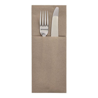 En silvergaffel och en kniv ligger i en Starpak 100 bestickficka, Airlaid 40 cm x 48 cm med bestickveck och skapar därmed en elegant bordsdukning på enkel vit bakgrund.