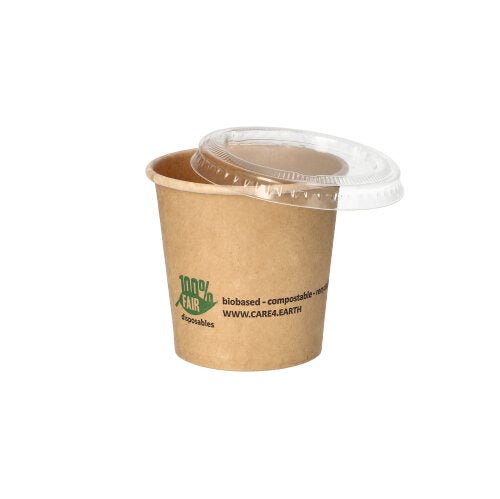 En PAPSTAR 50 portionsbägare av brunt papper från PAPSTAR GmbH med grön logotyp och text ligger diagonalt, klart plastlock ovanpå. Idealisk som miljövänlig portionsbägare på vit bakgrund.