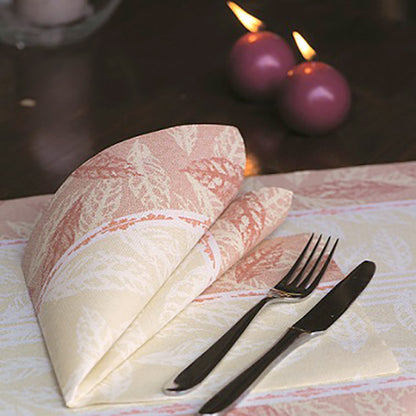 En vikt röd servett PAPSTAR 50 servetter "ROYAL Collection" 1/4-vikning 40 x 40 cm från PAPSTAR GmbH ligger bredvid gaffel och kniv på ett dukat bord. I bakgrunden syns två brinnande lila ljus.