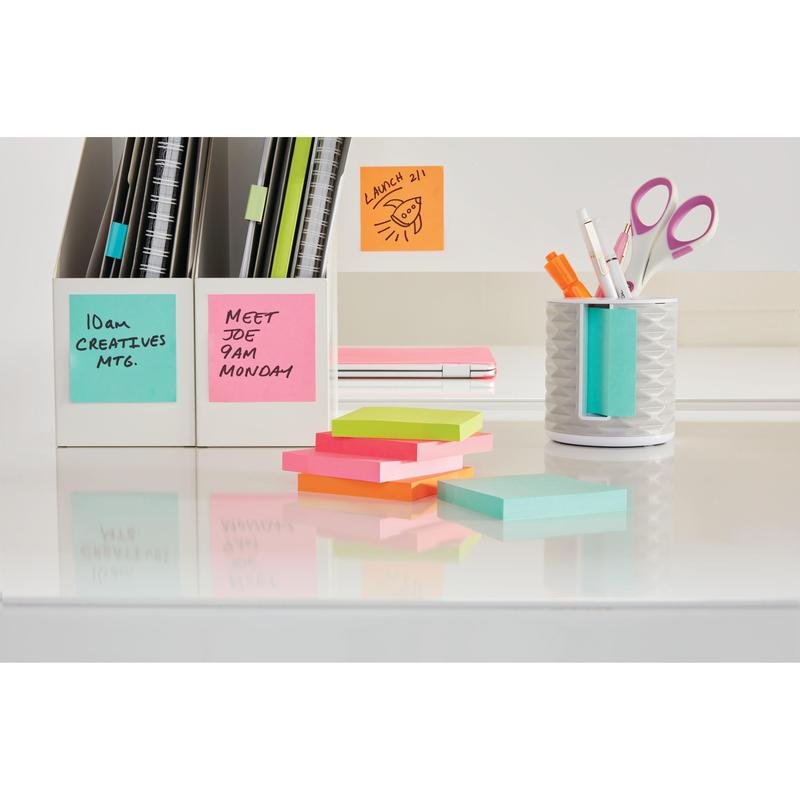 Ett välordnat skrivbord med de färgglada Post-it® Notes-kub (76x76mm, 450 blad/block, 100% PEFC) från 3M Deutschland GmbH, en vit pennkopp fylld med pennor och saxar, anteckningsböcker och kortlådor. Klisterlapparna är märkta med handskrivna påminnelser.