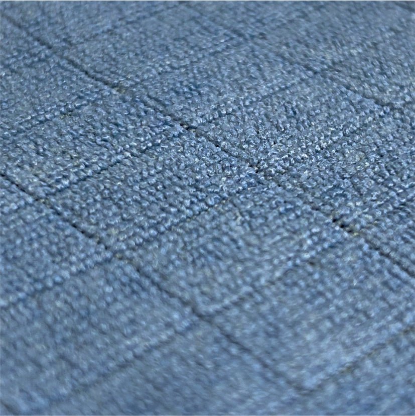 Närbild av Arcora Floor-Clean mikrofiber golvduk från Arcora International GmbH: en tygyta med ett rutnät av små, upphöjda blågrå rutor, idealisk för golvrengöring. Förpackningen innehåller 10 stycken.