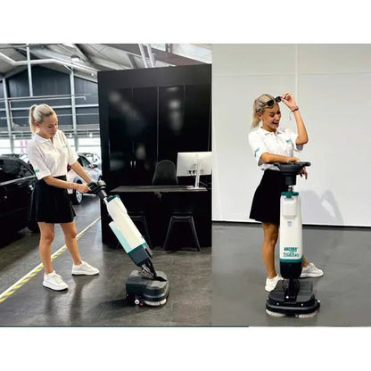 Två kvinnor i vita skjortor och svarta kjolar använder Arcora International GmbH Tiger 40 golvrengöringsmaskinen | Kartong (1 styck) inomhus; en manövrerar maskinen medan den andra leende presenterar deras professionella rengöring.