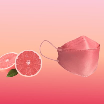 En partikelfiltrerande Altruan designermask (FFP2-standard) är elegant placerad bredvid två grapefrukthalvor på en rosa bakgrund med färgövergång, vilket framhäver dess stilfulla design och ergonomiska passform.