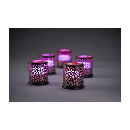 Åtta cylindriska mini-ljushållare från Duni GmbH:s Multicolour LED-set lyser genom ett utskuret mönster på en grå yta mot en mörk bakgrund.