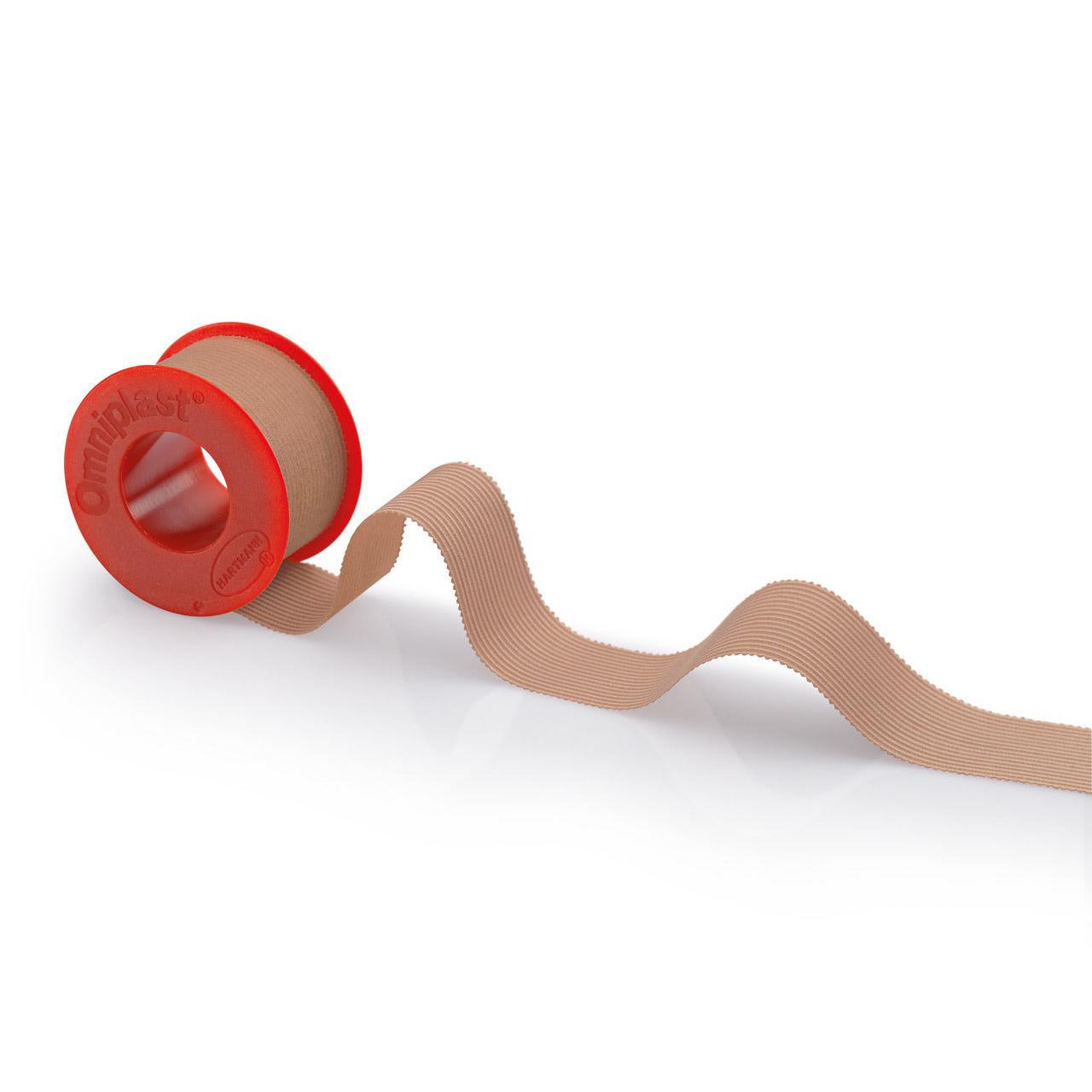 En rulle beige Hartmann Omniplast® spolplåster med en röd hållare med texten ”Paul Hartmann AG” på vit bakgrund. Bandet löper vågigt till höger sida av hållaren.