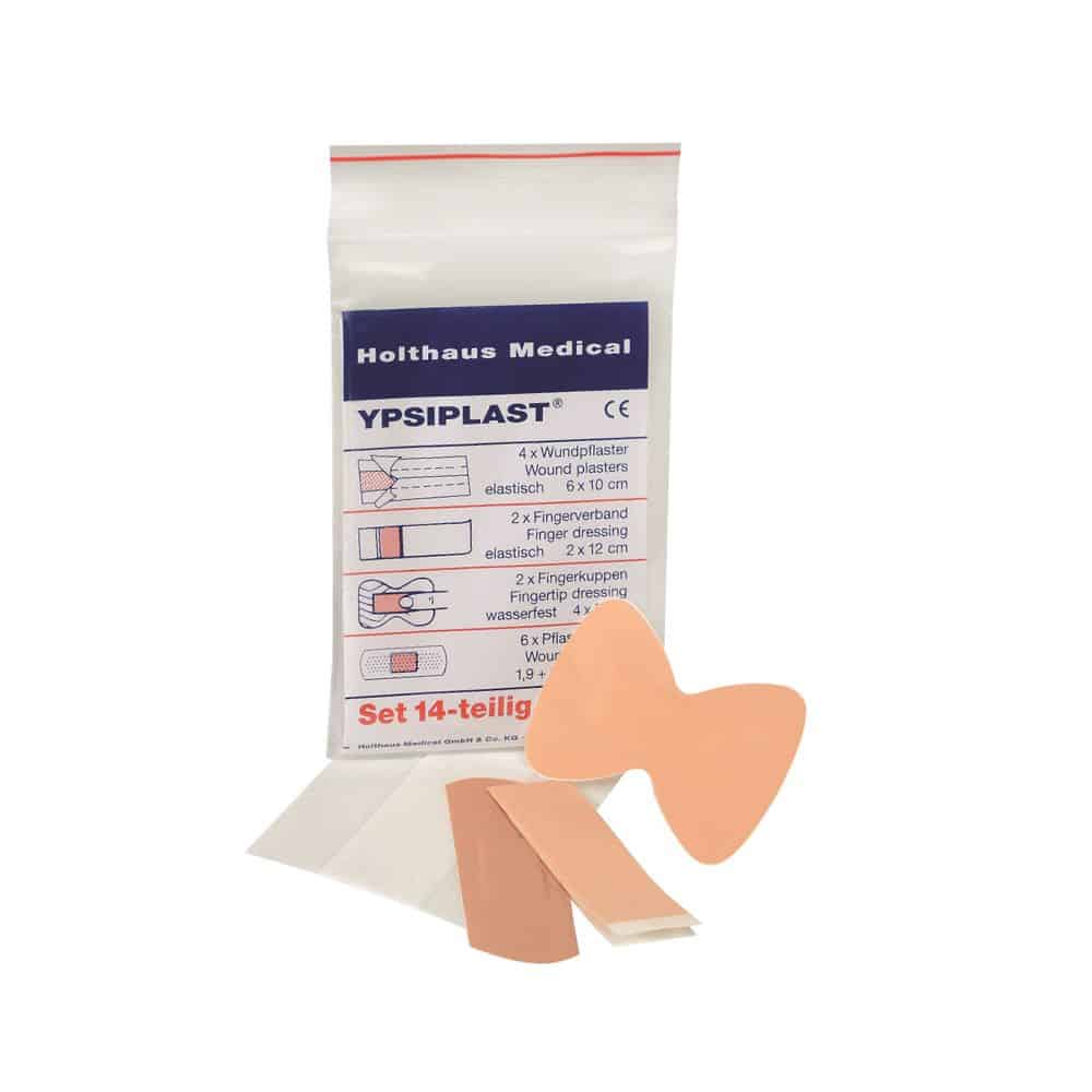 Avbildad är en förpackning Holthaus Medical YPSIPLAST® plåsterset, DIN från Holthaus Medical GmbH & Co. KG. Det 14-delade setet innehåller 4 sårplåster (6 x 10 cm), 2 fingertopps- och fingerförband, 2 fjärilsplåster och 6 små häftplåster. Några av artiklarna är avbildade utanför förpackningen.