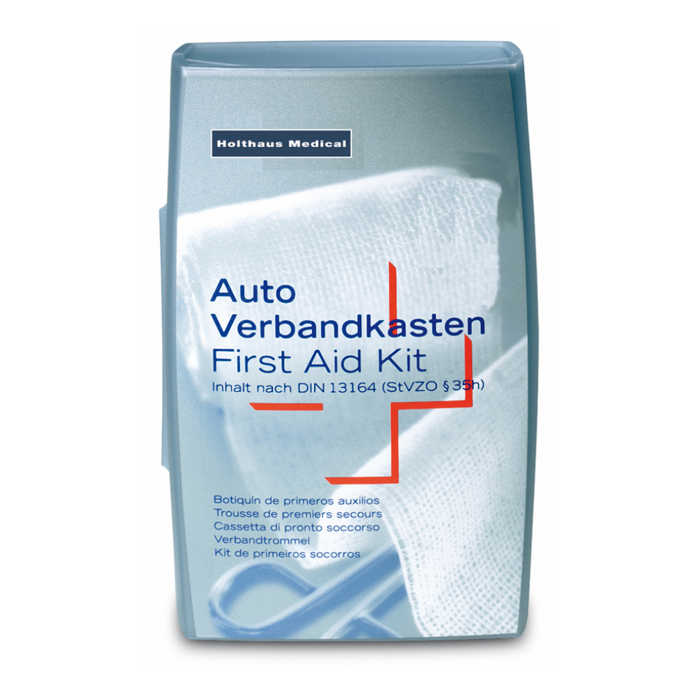 Ett silverfärgat Holthaus Silver Första Hjälpen-set från Holthaus Medical GmbH & Co. KG. Texten på omslaget är flerspråkig med angivelsen „Auto Verbandkasten / Erste-Hilfe-Kasten“ och anger att det överensstämmer med DIN 13164 (StVZO §35h). I bakgrunden syns ett vitt medicinskt bandage, idealiskt för medicinska nödsituationer.