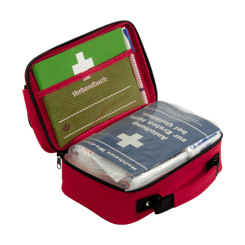 En kompakt röd Holthaus förbandsväska Office plus, DIN 13 157 från Holthaus Medical GmbH & Co. KG, med svart handtag som kan öppnas för att avslöja innehållet. Inuti finns en grön bruksanvisning och en blå Holthaus förbandsväska dekorerad med ett vitt kors och tysk text. Första hjälpen-utrustningen är överskådligt placerad i nätfickor och fack och är därför idealisk för kontorsmiljöer.