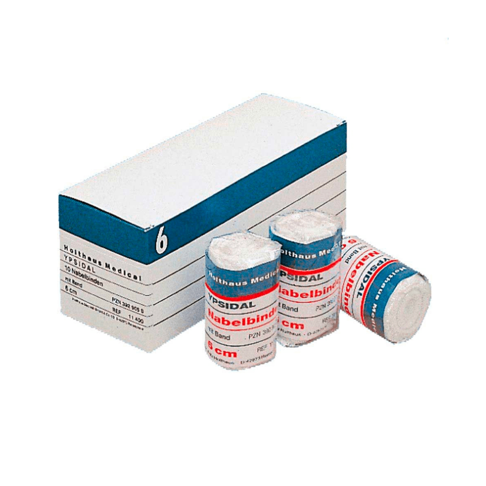 I en vit kartong med texten ”Holthaus YPSIDAL navelbandage” och blå och vita ränder ligger en rulle med ett medicinskt bandage i storleken 6 cm × 2 m, tillverkat av 100 % bomull. Framför kartongen ligger tre rullar med elastiskt bandage av märket ”Mollelast Medical” med texten ”8 cm”.