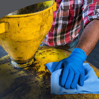 En person i rutig skjorta och med blå handskar rengör en gul industrimaskin med Kimberly-Clark GmbH WypAll® X80 PowerClean - stor rulle (31,00 cm x 31,50 cm) och demonstrerar därmed professionell användning inom industrin eller verkstaden.