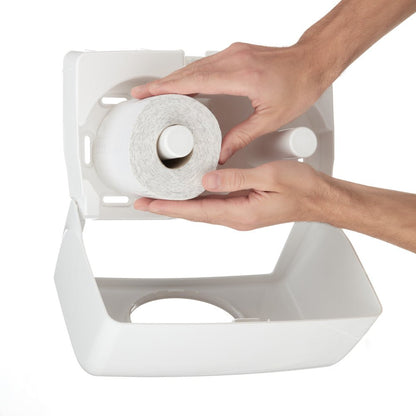 En person lägger in en ny rulle Kleenex® toalettpappersrullar små rullar från en 8 x 12-förpackning från Kimberly-Clark GmbH i en vit plastdispenser med öppet lock.