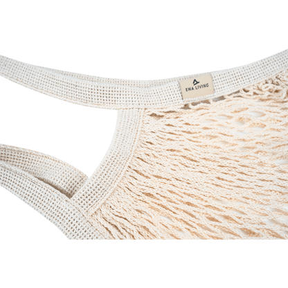 Närbild av det beige ENA Living shoppingnätet från Abena Re-Seller GmbH med tjocka, flätade handtag och en liten "ENA LIVING"-skylt. Idealisk för miljömedvetna inköp. Förpackningsenhet: kartong (24 förpackningar), bakgrund: vit.
