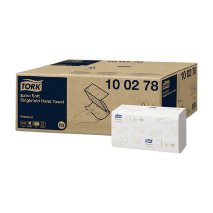Förpackningen för Tork 100278 extra mjuka zickzack-handdukar Premium H3 2-lager kombinerar hygien och elegans med sin brun-vita design. Den större bruna lådan visar produktdetaljerna, medan den mindre vita lådan framhäver Premium-H3-handduksdesignen med gröna bladmotiv och Tork-logotypen som representerar varumärket TORK – Essity Professional Hygiene Germany GmbH.