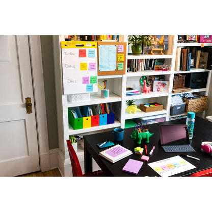 Ein aufgeräumtes Heimbüro mit weißen Regalen, einem schwarzen Tisch mit Notizbüchern, einem iPad, Stiften, einer Wasserflasche und bunten Post-it® Super Sticky Z-Notes (Boost Collection) von 3M Deutschland GmbH auf einem Flipchart mit der Aufschrift "To-Do, Doing, Done".