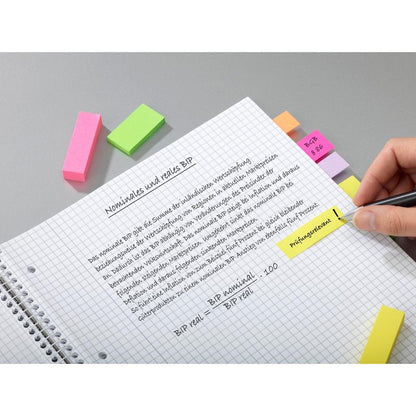 En hand lyfter en anteckning i en spiralanteckningsbok med tysk text om BNP. På anteckningarna finns Post-it® Page Marker från Energetic Collection (3M Deutschland GmbH, 25 mm x 76 mm, 3 block/förpackning) och färgade klisterremsor fästa.