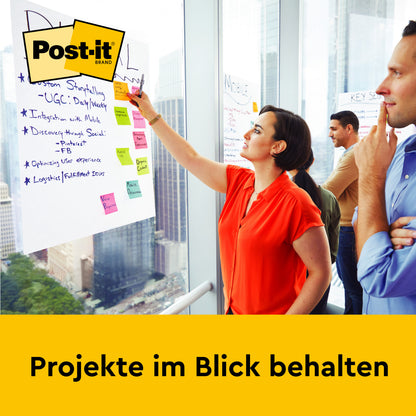 Eine Frau schreibt Notizen auf ein Post-it® Super Sticky selbsthaftendes Meeting Chart/Flipchart (63,5 x 76,2 cm, 30 Blatt, 2 Blöcke) von 3M Deutschland GmbH am Fenster, während zwei Männer zusehen. "Projekte im Blick behalten" steht darunter.