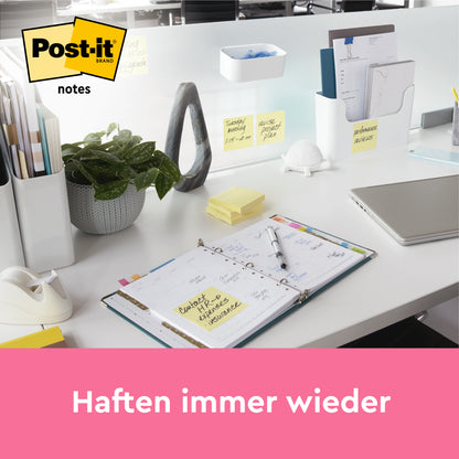 Ein aufgeräumter weißer Schreibtisch mit Bürobedarf, Pflanze, Laptop und aufgeschlagenem Planer ist mit Post-it® Notes Gelb (51x76 mm, 100 Blatt/Block, 12 Blöcke/Packung) von 3M Deutschland GmbH ausgestattet. Haftnotizen sind sichtbar; "Haften immer wieder." Logo oben links.